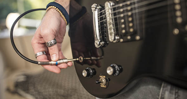 Close up of man's hand plugging electric guitar